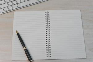 computadora con teclado y libro con bolígrafo en el escritorio. foto