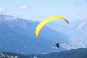 parapente volando en el cielo azul sobre las hermosas montañas. foto