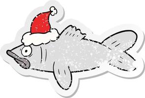 distressed sticker cartoon of a fish wearing santa hat vector