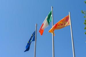 bandera italiana de la ue y veneto local ondeando en el viento foto