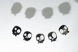 Skulls cut out of black paper on a white background, preparation for Halloween. photo