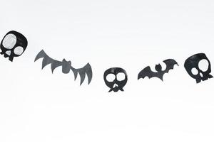 Skulls and flying bats cut out of black paper on a white background, preparation for Halloween. photo