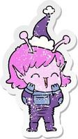 distressed sticker cartoon of a alien girl giggling wearing santa hat vector