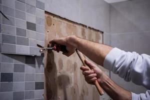 worker remove demolish old tiles in a bathroom photo