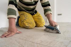 Tilers filling the space between ceramic wood effect tiles photo