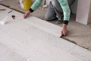 worker installing the ceramic wood effect tiles on the floor photo