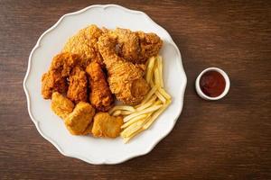 pollo frito con papas fritas y nuggets en un plato foto