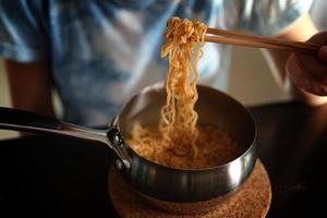 comer fideos instantáneos en una olla de aluminio foto