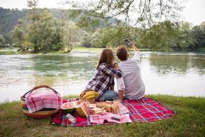 Couple taking a selfie by mobile phone while enjoying picnic time photo