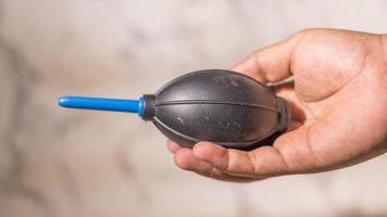 Close up male hand holding a manual hand air blower on abstract white background photo