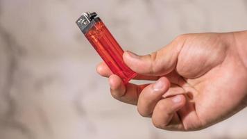 hand of man lighting cigarette lighter against bright background photo