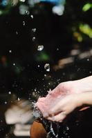 salpicando agua dulce en manos de mujer foto