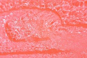 desenfoque borroso transparente color naranja claro agua tranquila textura superficial con salpicaduras y burbujas. fondo de naturaleza abstracta de moda. onda de agua a la luz del sol con espacio de copia. color naranja gota de agua foto