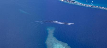 Aerial picture of turquoise blue tropical ocean lagoon, white sandy beach, sandbank coral reef shallow water with a boat. Nature perfection in Maldives sea. Luxury life experience, peaceful landscape photo