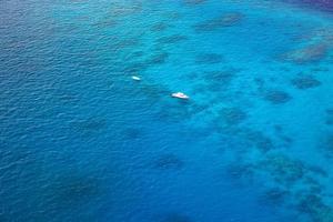 imagen aérea de la laguna oceánica tropical azul turquesa, playa de arena blanca, arrecife de coral de banco de arena aguas poco profundas con un barco. perfección de la naturaleza en el mar de maldivas. experiencia de vida de lujo, paisaje tranquilo foto