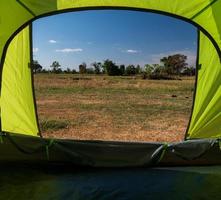 Traveler green tent Camping outdoor travel. View from the tent inside on the blue sky sun in the summer landscape. during the evening of the day suitable for sleeping and resting the body