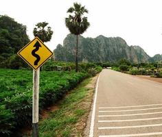 long road that travel through various village in rural Thailand passing through forest meadows and mountain on clear day blue sky white cloud in summer Suitable driving photo