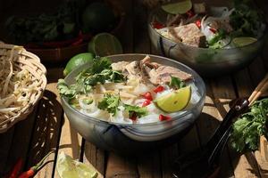 Vietnamese Noodle Soup Pho Bo with Beef on a Bamboo Table photo