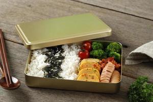 Dosirak Korean Lunch Box Contain Steamed Rice with Gyeranmari, Sausage, Kimchi, Tomato, and Steamed Broccoli photo