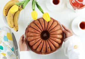 vista superior mano femenina sostenga un plato grande con pastel de pan de plátano foto
