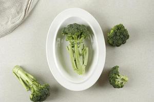 Fresh Broccoli on White oval Plate, Top View photo