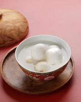 Tang Yuan, Chinese Glutinous Rice Dumpling Balls with Sugar Ginger or Palm Sugar Syrup on Red Chinese on Black Background for Winter Solstice New Year Festival photo