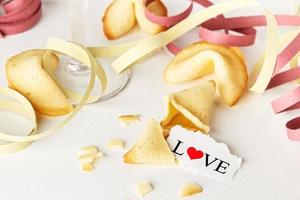 Cookies shaped like tortellini with the word love written on a paper and a glass of champagne with streamers.Horizontal image. photo