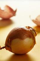 Onion with backlight with onion skins at the bottom on yellow surface. Healthy life concept. Vertical image. photo