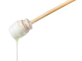 white honey pouring from wooden stick close up photo