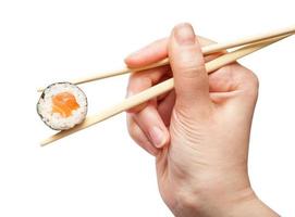 los palillos sostienen un maki roll de sake con pescado salmón foto