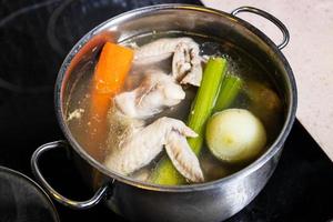 chicken wings soup is cooked in steel stewpot photo