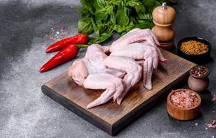Raw chicken wings with ingredients for cooking on a wooden cutting board photo