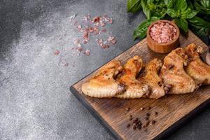alitas de pollo al horno con semillas de sésamo y salsa en una tabla de cortar de madera foto
