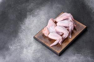 Raw chicken wings with ingredients for cooking on a wooden cutting board photo