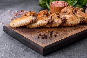 Baked chicken wings with sesame seeds and sauce on a wooden cutting board photo