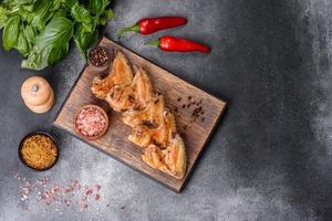 Baked chicken wings with sesame seeds and sauce on a wooden cutting board photo