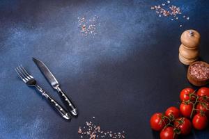 Cherry tomatoes with spices and silverware o dark table photo