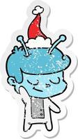 friendly distressed sticker cartoon of a spaceman wearing santa hat vector