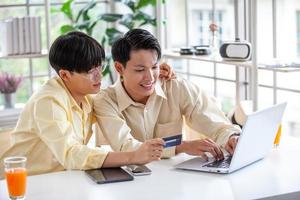 Asian gay couples are using laptop or shopping online with credit card,  LGBTQ concept.