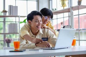 las parejas gays asiáticas usan una computadora portátil o compran en línea con tarjeta de crédito, concepto lgbtq.