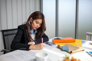 Portrait of Asian beautiful business woman working at the office, writing a document on table. photo