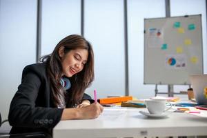 Portrait of Asian beautiful business woman working at the office, writing a document on table. photo