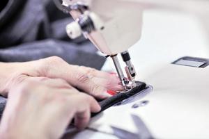 manos de costurera usando máquina de coser foto