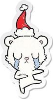 crying polar bear distressed sticker cartoon of a wearing santa hat vector