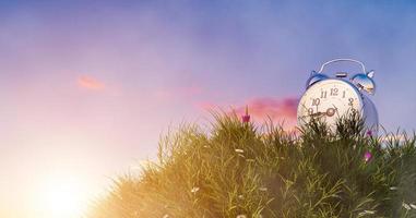 Alarm clock on small hill and grass meadow, environmental with time concept photo