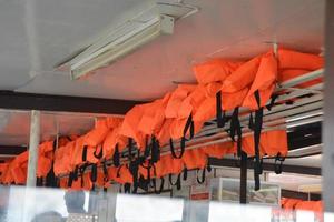 chaleco salvavidas en color naranja importante para la seguridad de la vida colocado en la plataforma del barco. foto