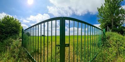 gran puerta de metal verde a un campo verde foto