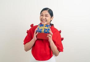 Feliz mujer asiática vistiendo camisa roja con caja de regalo a mano para el festival de Navidad foto