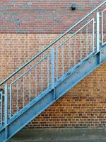 Close up view on metallic stairs in front of a brick wall. photo