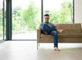 man on sofa using tablet computer photo